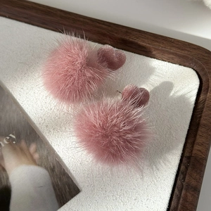 Detail of pink faux fur pom pom earrings with heart velvet stud for autumn winter style