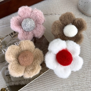 Gros plan de quatre pinces à cheveux fleurs en peluche aux centres colorés sur fond doux