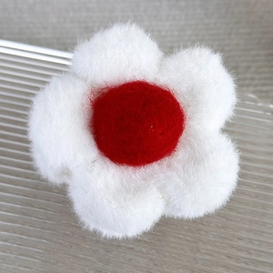 Détail macro d'une pince à cheveux fleur en peluche avec pétales blancs et cœur rouge