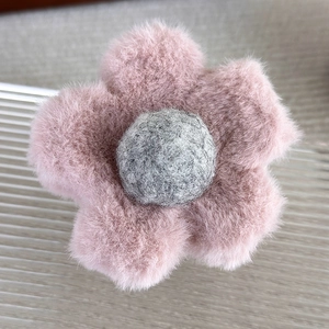 Gros plan détaillé de la pince à cheveux fleur en peluche aux pétales roses et cœur gris