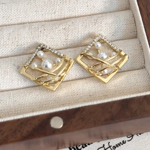 Macro detail of geometric rhombus earrings with gold frame, inlaid pearls and small diamonds