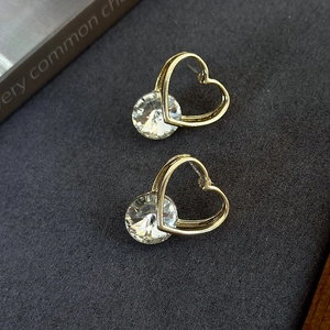 Detail of heart-shaped gold studs with large round cubic zirconia on a dark surface