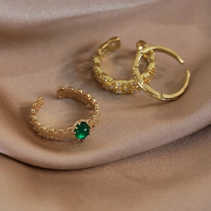 Set di anelli vintage dorati con smeraldo su seta champagne con dettagli di perline