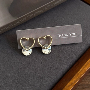 Close-up of heart-shaped gold studs with large round crystal on a gift card