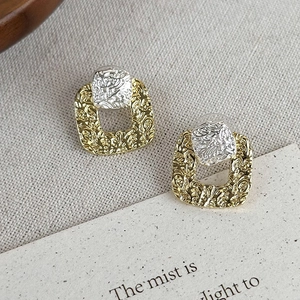 Detailed macro view of retro square earrings with hammered gold and silver texture