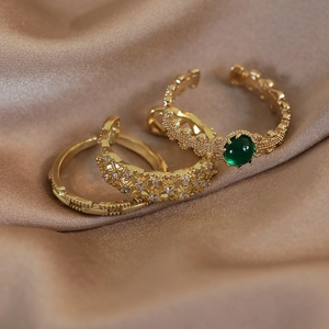 Dettaglio di anelli a fascia in oro con pietra verde smeraldo e intarsio di zirconi