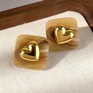 Dettaglio di orecchini vintage quadrati marroni con cuore dorato in metallo lucido