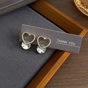 Elegant heart shaped gold stud earrings with round clear zircon on display card