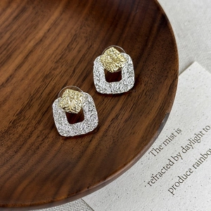Detail view of retro gold and silver mixed metal earrings with hammer texture