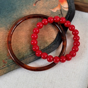 New Year set with dark red beaded bracelet and amber pattern bangle on a fan
