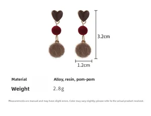 Détail des boucles d'oreilles cœur à pompon mesurant 3,2 cm par 1,2 cm de style doux