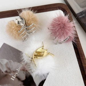 Trois pinces à cheveux en peluche en kaki, rose et blanc sur plateau bois et base métal