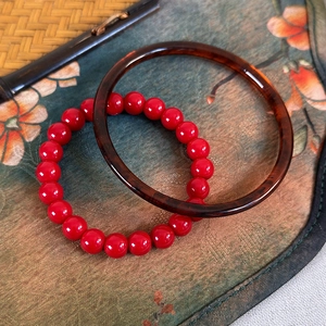 Detail of red beaded bracelet and amber texture resin bangle in retro Chinese style