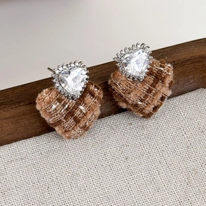 Dettaglio di orecchini vintage a cuore con tessuto tweed marrone e zirconi scintillanti