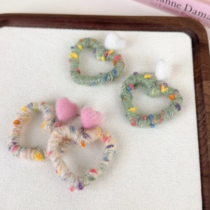 Rainbow knit heart earrings with plush pompoms in a stylish minimalist display tray