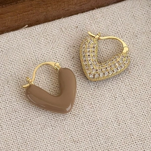 Dettaglio di orecchini a cuore asimmetrici con smalto moka e pietre di zircone bianco