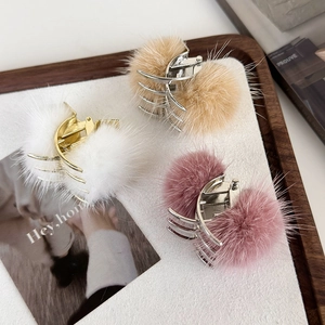 Gros plan de pinces à cheveux en fausse fourrure blanche, kaki et rose avec finition dorée