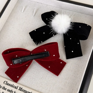 Détail de barrettes noeud en velours avec strass et pompons en fourrure sur présentoir