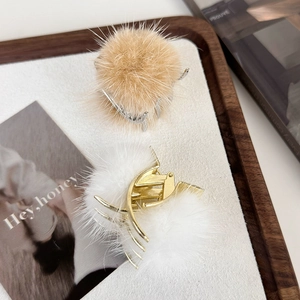 Détail de pinces à cheveux en fausse fourrure pelucheuse blanche et beige avec métal