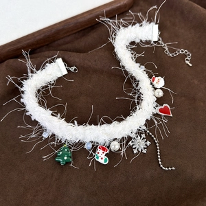Detailed close-up of white plush Christmas choker with festive charms on brown fabric