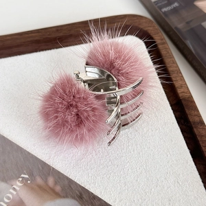 Détail de pompons en fourrure rose sur pince à cheveux en métal argenté et peluche