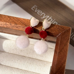 Vue détaillée des clous d'oreilles cœur et des boucles d'oreilles pompons en fausse fourrure