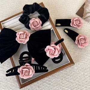 Elegant black velvet and pink camellia hair accessory set in a decorative wooden tray