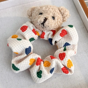 Détail du chouchou ours en peluche avec coeurs colorés et texture de tissu doux