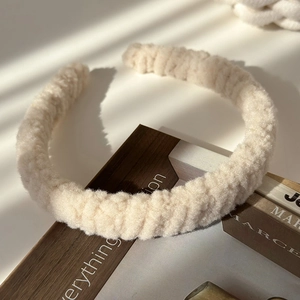 Gros plan d'un serre-tête en peluche crème avec texture douce sur des livres vintage