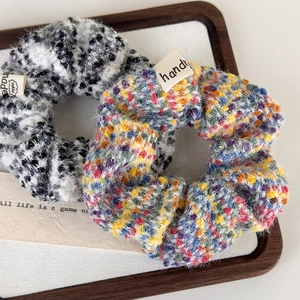 Set of two colorful tweed plush scrunchies with handmade labels on a wooden tray