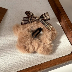Close-up of a fluffy brown star hair clip with a vintage plaid bow detail