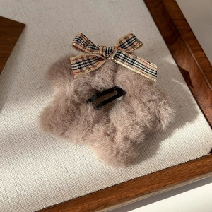 Close-up of vintage brown wool star hair clip with plaid bow on a canvas background