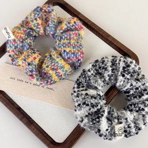 Colorful fuzzy scrunchie with plush texture and woven labels in a stylish white tray