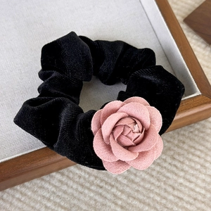 Macro shot of elegant black velvet hair scrunchie with a detailed pink camellia flower
