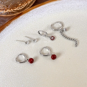 Detail view of New Year red earrings set including pearl and letter charms on ceramic tray