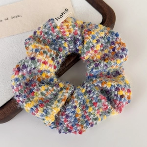 Detail of colorful knitted bouclé hair scrunchie with a white handmade fabric label