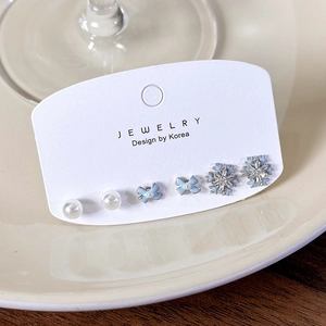 Detail of 3-pair earring set with blue bow, snowflake studs, and pearls on display card