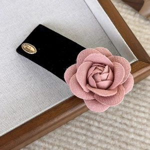 Detail of black velvet hair claw with pink 3D camellia flower and gold Love is Forever plate