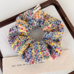 Detailed view of colorful knit scrunchie with soft plush texture and handmade label