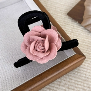 Detail of elegant black velvet hair claw clip with a 3D pink fabric camellia flower