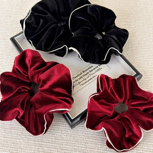 Détail de chouchous en velours noir et bordeaux avec une bordure blanche contrastée