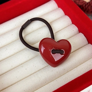 Dettaglio macro di un cuore rosso lucido su elastico per capelli in una scatola portagioie rossa
