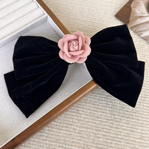 Detail of elegant black velvet hair clip featuring a pink camellia flower texture