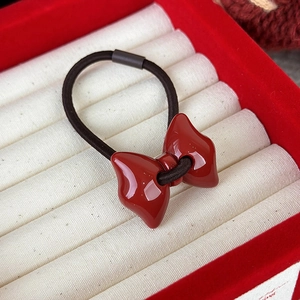 Dettaglio di un elastico per capelli con fiocco rosso in resina e fascia elastica nera