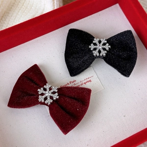 Détail de barrettes à nœuds en velours avec flocons de neige strassés en rouge et noir