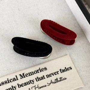 Close-up of vintage velvet hair clips in black and wine red with soft flocking texture