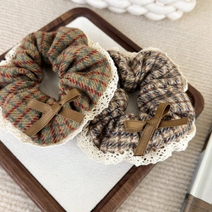 Détails de chouchous en tweed avec dentelle blanche et nœuds en ruban côtelé marron