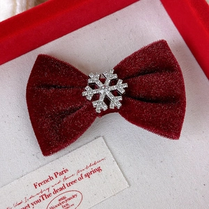 Détail de la pince à cheveux noeud en velours rouge avec flocon de neige en strass brillant