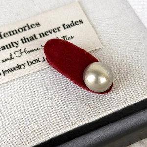 Detailed macro view of dark red velvet hair clip with a silver metallic bead accent