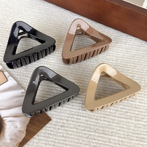 Quatre pinces à cheveux triangulaires ajourées aux tons terre sur tissu beige ondulé
